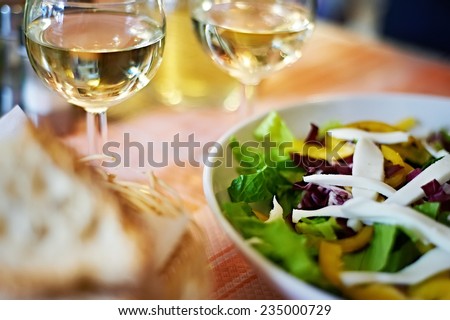 Glasses of white wine and a salad on the table cafe