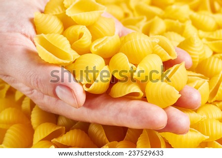 Pasta in the womens hands on background of pasta