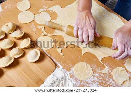 Woman prepare dough with rolling pin for dumplings indoors