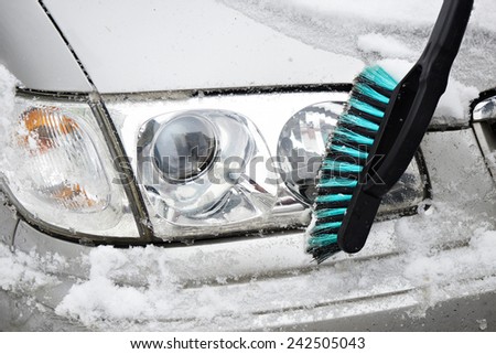 Man cleans a car from the snow with a brush