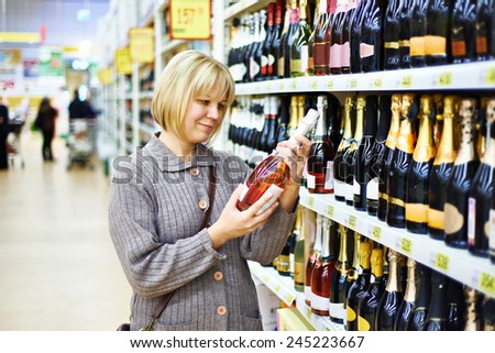 Woman choosing pink wine in supermarket