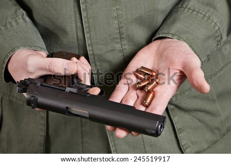 Soldier in uniform holding a gun Colt cartridges to it