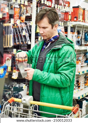 Man Buying Handsaw In Hardware Store