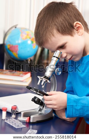 Boy uses a microscope at home learning table