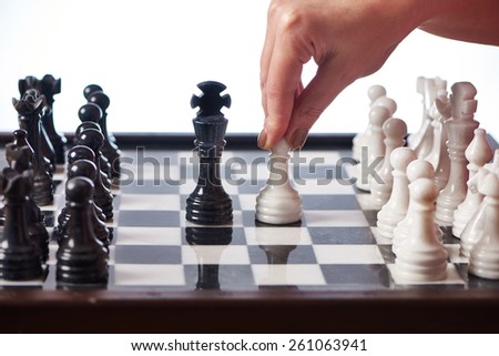 Hand with white pawn moves to black king closeup