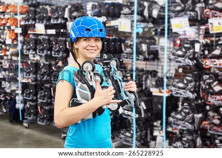 Girl in a helmet and with rollers in the sports shop