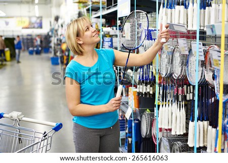 Woman chooses badminton racquet in sport shop