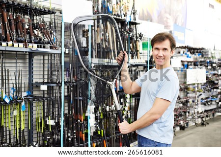Man chooses landing net for fishing in the sports shop