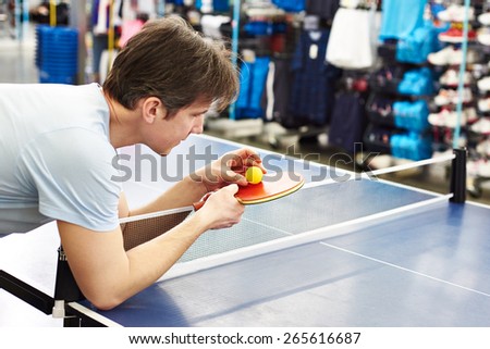 Man chooses table tennis racquet in sport shop