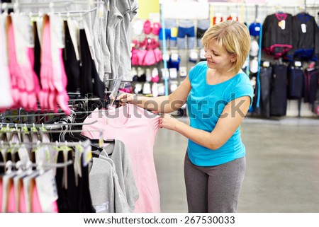 Happy woman shopping t-shirt in sport shop