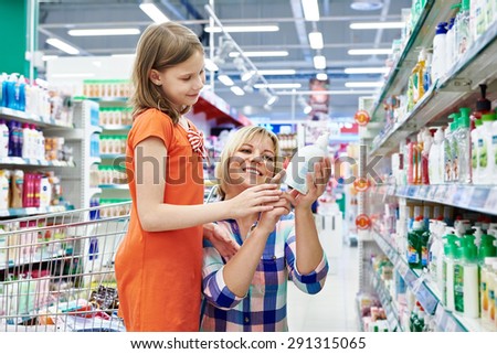 Mother and daughter shopping shampoo in supermarket