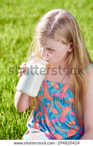 Girl with long hair drink milk in sunny meadow