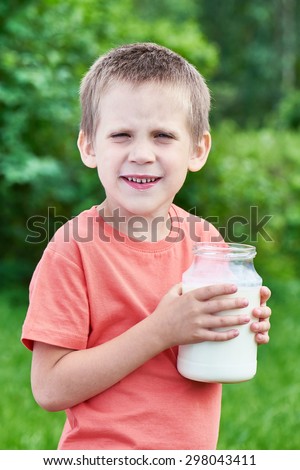 Boy with glass jar of fresh milk in summer day