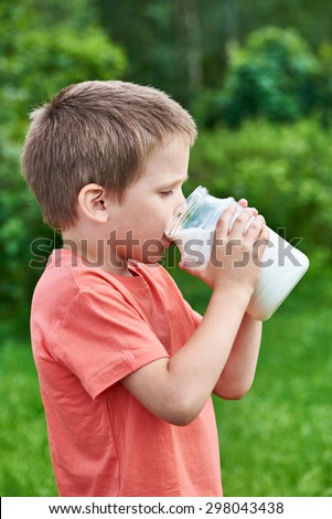 Boy drinks milk in sunny garden