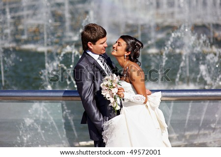 Happy bride and groom on wedding walk near fountain