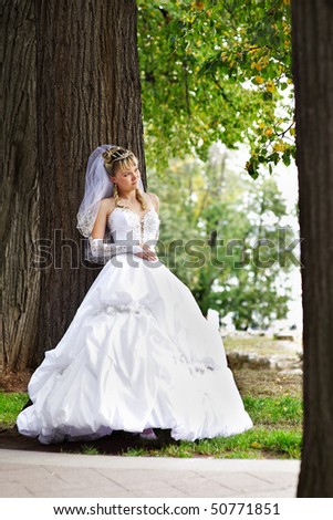 Bride in wedding stroll around the huge trees in the park