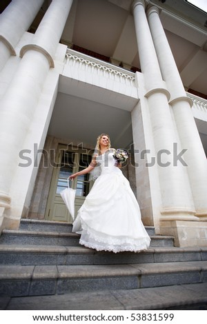 Happy bride with umbrella on entrance of palace