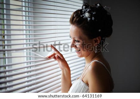 Happy bride at the window with the blinds