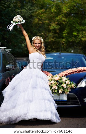 Happy bride with bouquet near wedding car with flowers