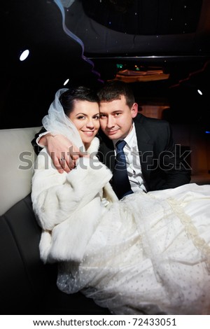 Elegant bride and groom in a wedding limousine