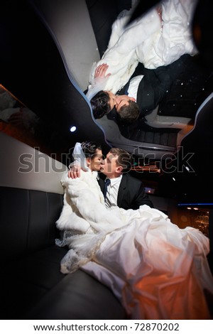 Gentle kiss bride and groom in wedding limousine