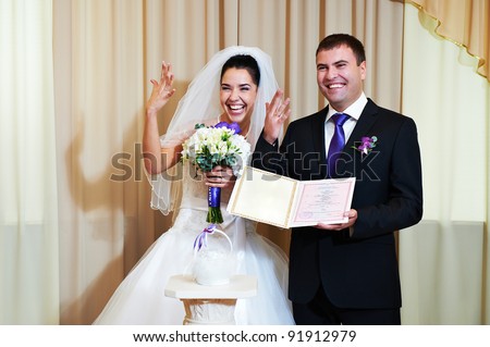Bride and groom showing their wedding rings and marriage certificate