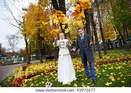 Bride and groom throw maple leaves on wedding walk