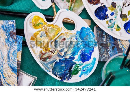Brushes, palette, paint and water on the table