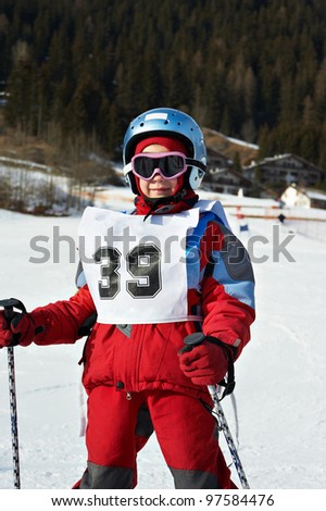 Child on helmet and with sports number  in the ski resort