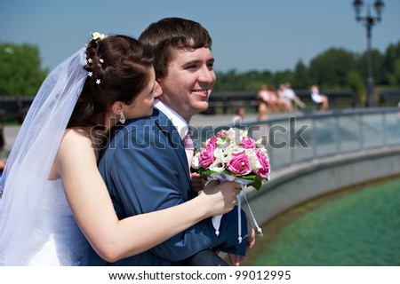 Happy bride and groom with bouquet at wedding walk in the park