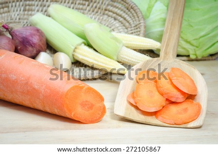 Chopped carrot slices on wooden cutting board and vegetables background