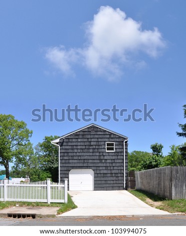 Two Story Wood Shingle Home White Garage Door Cement Driveway White Picket Fence Sunny blue sky cloud day