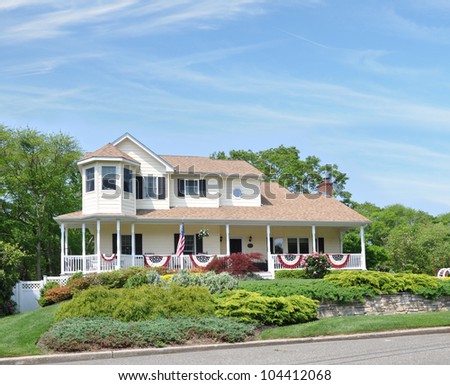 Large Suburban Home Decorated with American Flags for Memorial Day and July 4 Independence Holiday Sunny Blue Sky Day