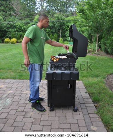 Man Cooking Vegetables Skewered on Outdoor Barbecue Grill