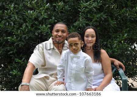 Two Family Generation Parents with Boy Child Wearing White sitting in front of Holly Bush