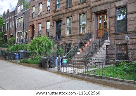 Brownstone Homes black rod iron fence with trash containers in Brooklyn New York USA