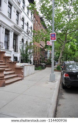 Sign No Honking No Parking on sidewalk of urban residential neighborhood in Manhattan New York lined with brownstone and limestone homes