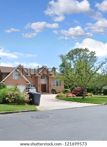 Trash Day Suburban Neighborhood Large Brick McMansion Style Architecture Home Sunny Blue Sky Day Clouds