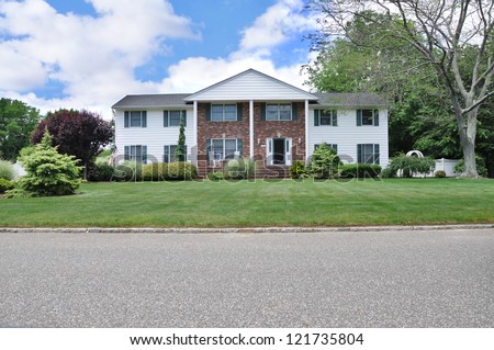 Suburban Georgian Style Home with landscaped front yard lawn in residential neighborhood American Flag