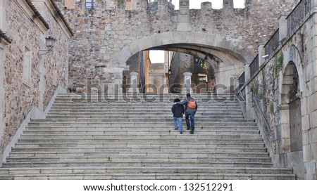 CACERES, SPAIN - MAR 18: Tourist climbing steps to enter through the 15th century Arco de la Estrella.  The main gateway to the medieval city  (currently called the old city) of Caceres Mar 18, 2013.