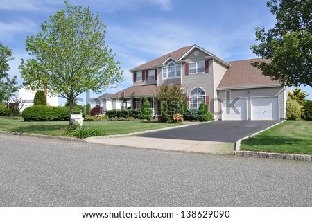 Suburban McMansion style Home Landscaped Freshly Cut Lawn Residential Neighborhood Sunny Blue Sky Day
