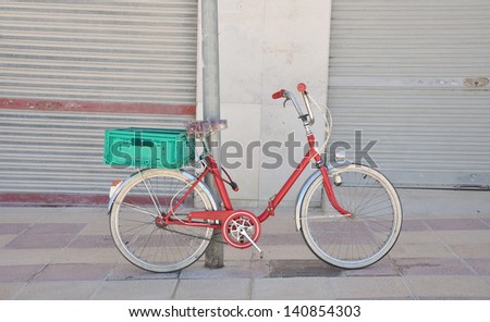 Red Girls Bicycle parked with green crate attached over back wheel in Campello a costal town in the province of costa blanca Alicante Spain Europe