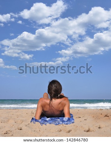 Woman on Beach looking at the waves blue sky with clouds