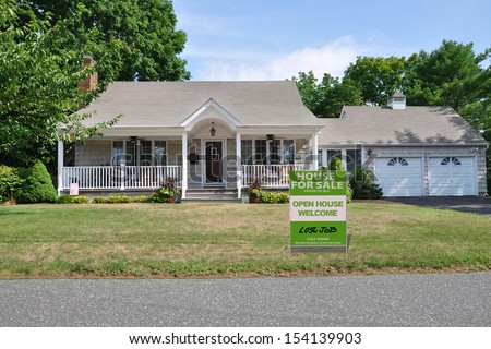 For Sale Real Estate Sign on Front yard lawn of Suburban Home in Residential Neighborhood USA