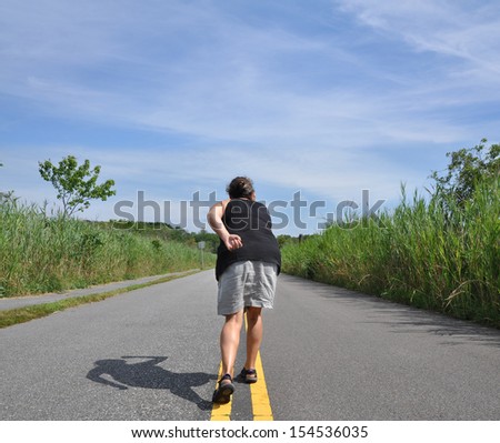 Woman Getting Ready to Run on Yellow Traffic Dividing Line on Road Lined with Nature