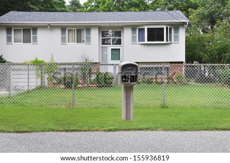Suburban High Ranch style home with Chain link fence curbside Mailbox residential neighborhood USA