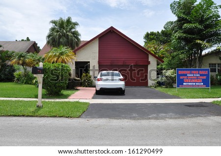 Real Estate For Sale Open House Welcome Sign on front yard lawn of Suburban Back Split Snout Garage style Home Parked Car Blue Sky Clouds