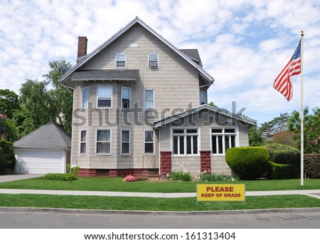 Keep off Grass Sign American Flag Victorian Style Suburban Home Residential Neighborhood USA Blue Sky Clouds