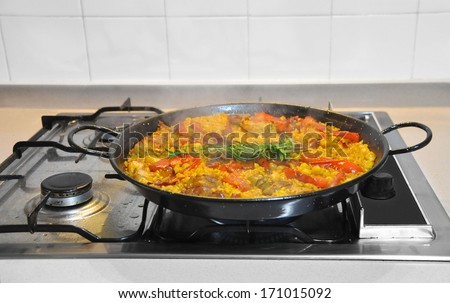 Fresh Rosemary on Rabbit Paella with Red Peppers Garbanzo Beans Cooking on Kitchen Stove Top