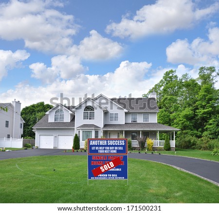 Sold Real Estate Sign (Another Success let us help you buy sell your next home) Suburban McMansion Style home Circle blacktop driveway two car garage residential neighborhood blue sky clouds USA